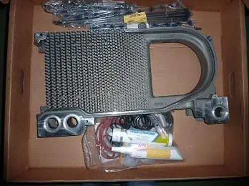 Mittelglied von Remeha in einer Kartonbox, bestehend aus einer metallischen Struktur mit Gittermuster und weiteren Komponenten in Klarsichtverpackungen.